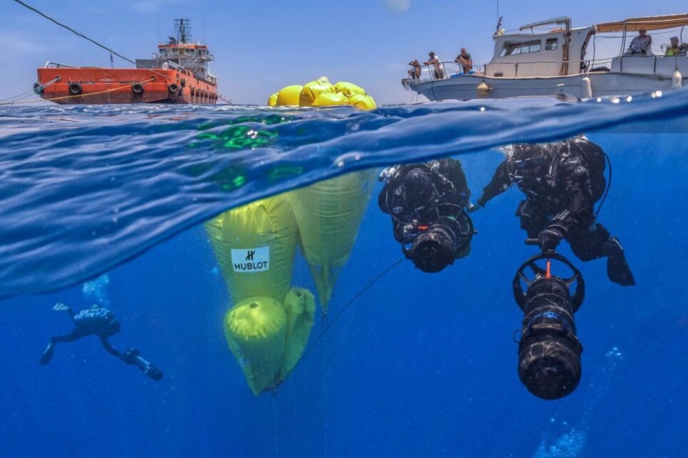 Divers from the 2014 Return to Antikythera expedition working at the wreck site, with lift bags at the surface above them