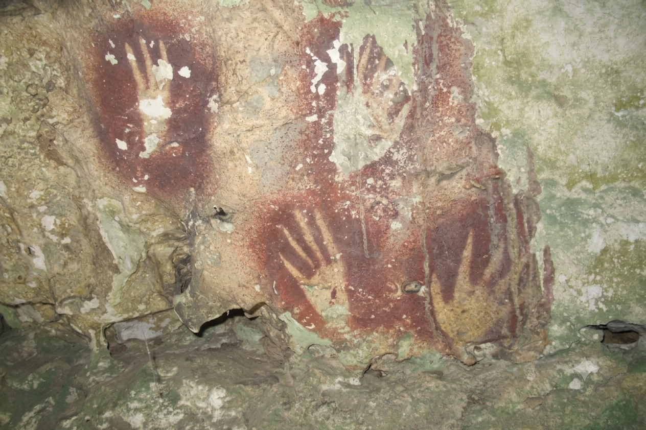 Red hand stencils on the limestone wall of a cave in Sulawesi