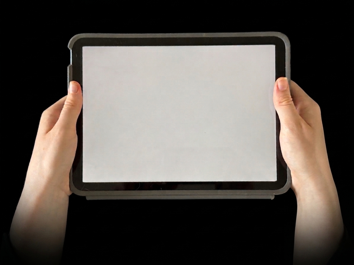 A photograph of hands holding a tablet in the dark, the closing words on its screen.